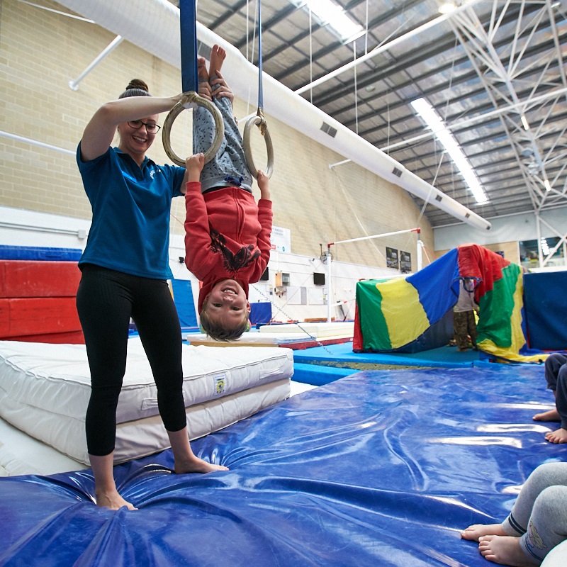 Young boy with coach on rings at kids gymnastics