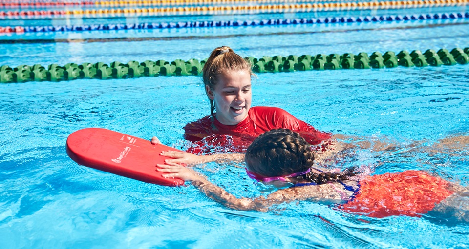 Swim instructor with student in outdoor pool