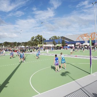 A photo of a game of netball being played on an outdoor court at the Gold Netball Centre in Jolimont, Perth