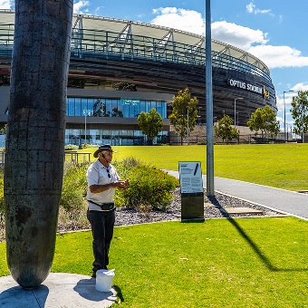 A photo of a man giving an Aboriginal cultural tour outside of Optus Stadium
