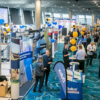 A photo of a conference with multiple stalls set up in an event space at Optus Stadium in Burswood, Perth