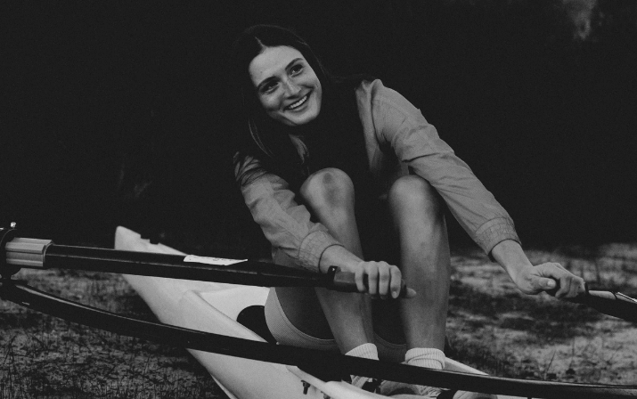 Close up photo of Gen Hart for the Just Add Venue Campaign Close up photo of Gen Hart in a speed row boat holding paddles in each hand for the Just Add Venue Campaign